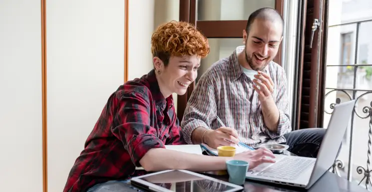 Zwei Freunde am Laptop lernen, um die Sparstrategie zu optimieren