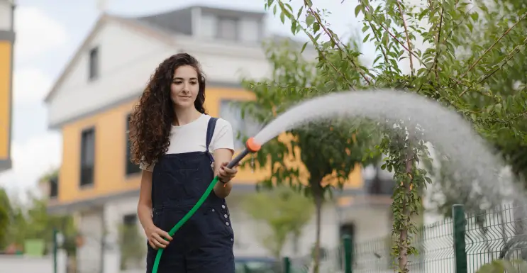 Frau tränkt den Garten sparsam, um den Wasserverbrauch zu senken