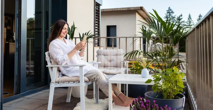 Frau geniesst den selbst und günstig gestalteten Balkon